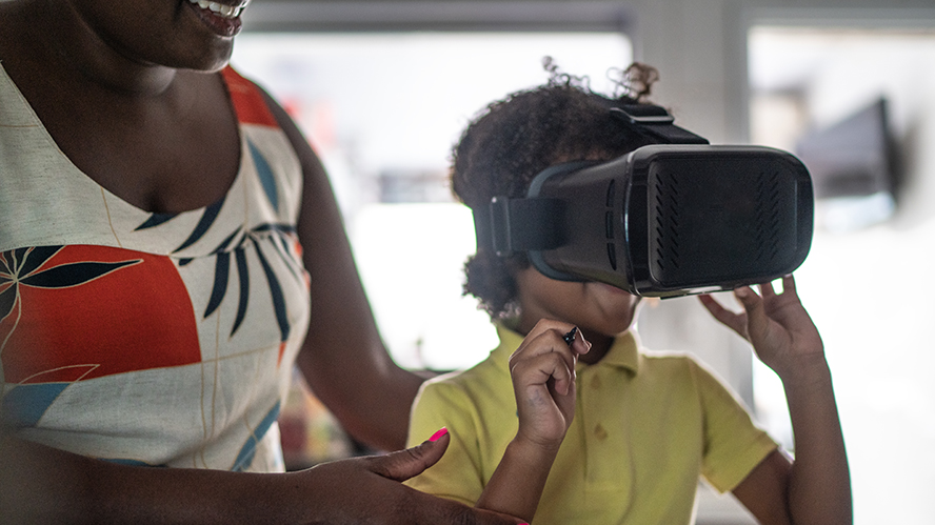 Smiling woman supporting young boy wearing VR headset